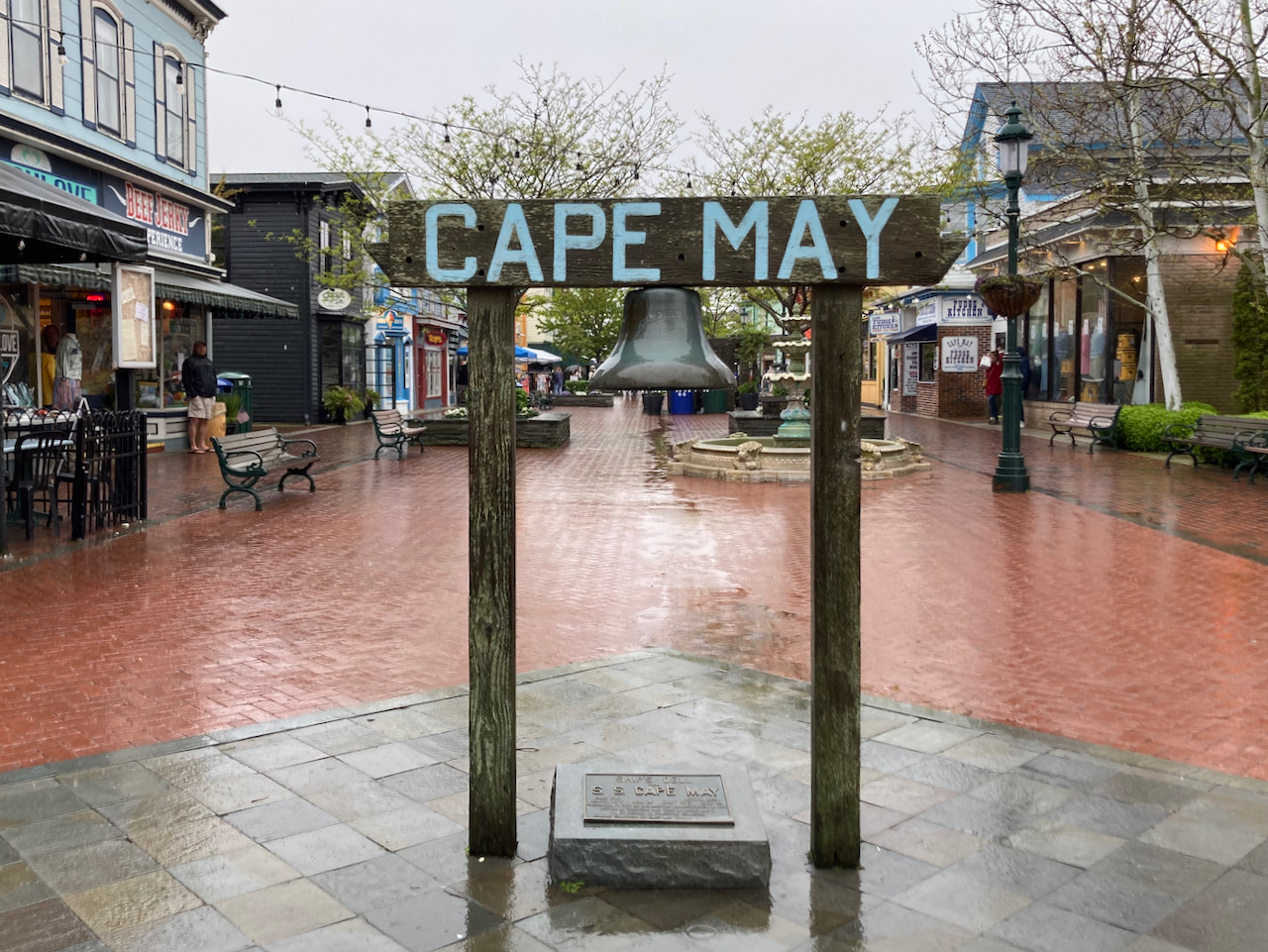 Deserted Washington Street Mall in Cape May. Sign in foreground says CAPE MAY with bronze bell hanging beneath it.