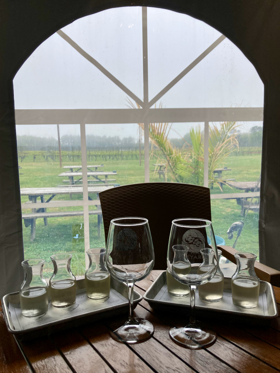 Table with tasting flights and two glasses. Window in the background looks out onto the vineyard.