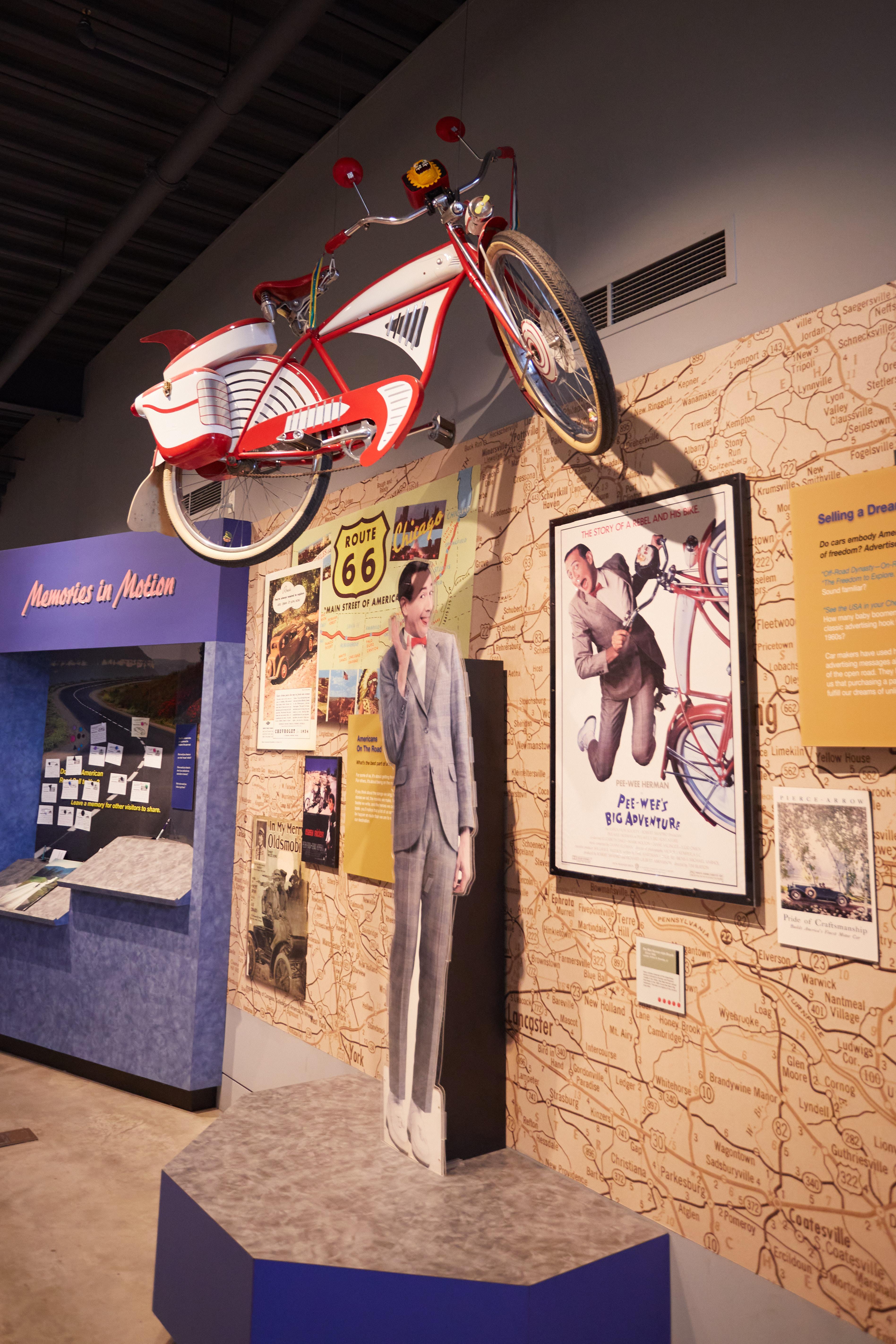 Exhibit on transportation in movies, including a cutout of Pee-Wee Herman and the red Schwinn bike from Pee-Wee's Big Adventure.