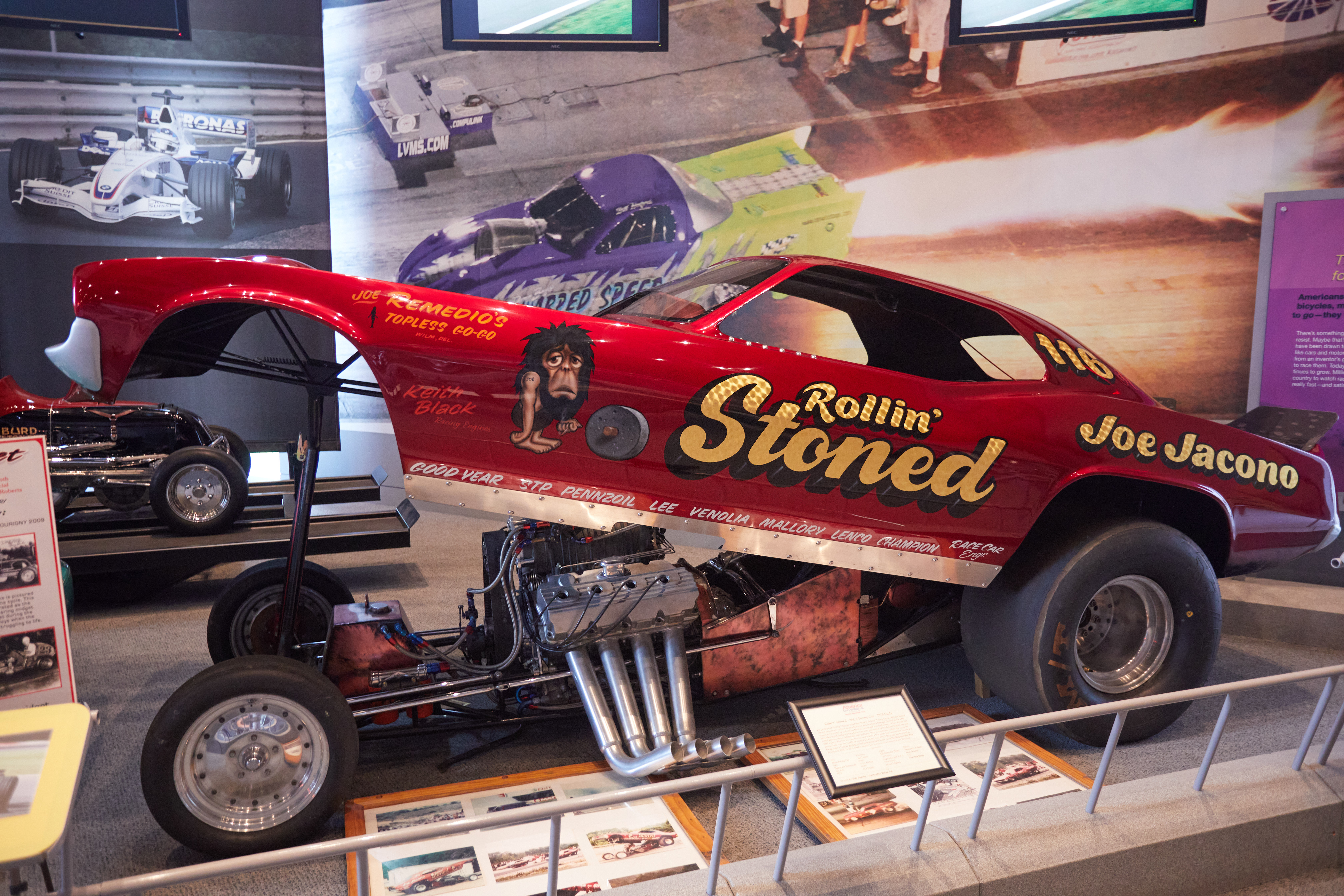 Red funny car with words ROLLIN' STONED on side.