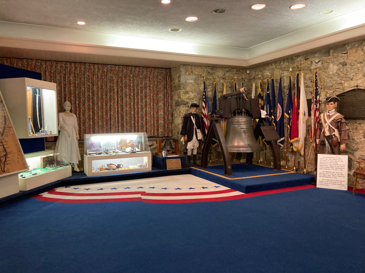 Exhibit on hiding of Liberty Bell in basement of Zion Reformed Church including display cases, mannequins dressed in Revolutionary-era attire, and a replace Liberty Bell.