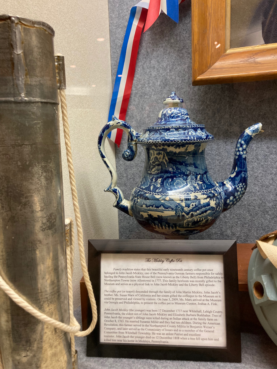 Blue and white enameled coffee pot in display case.