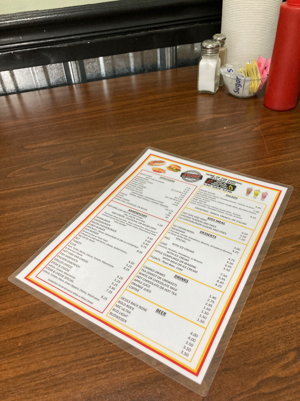 Menu on table, with condiments and paper towels in background.