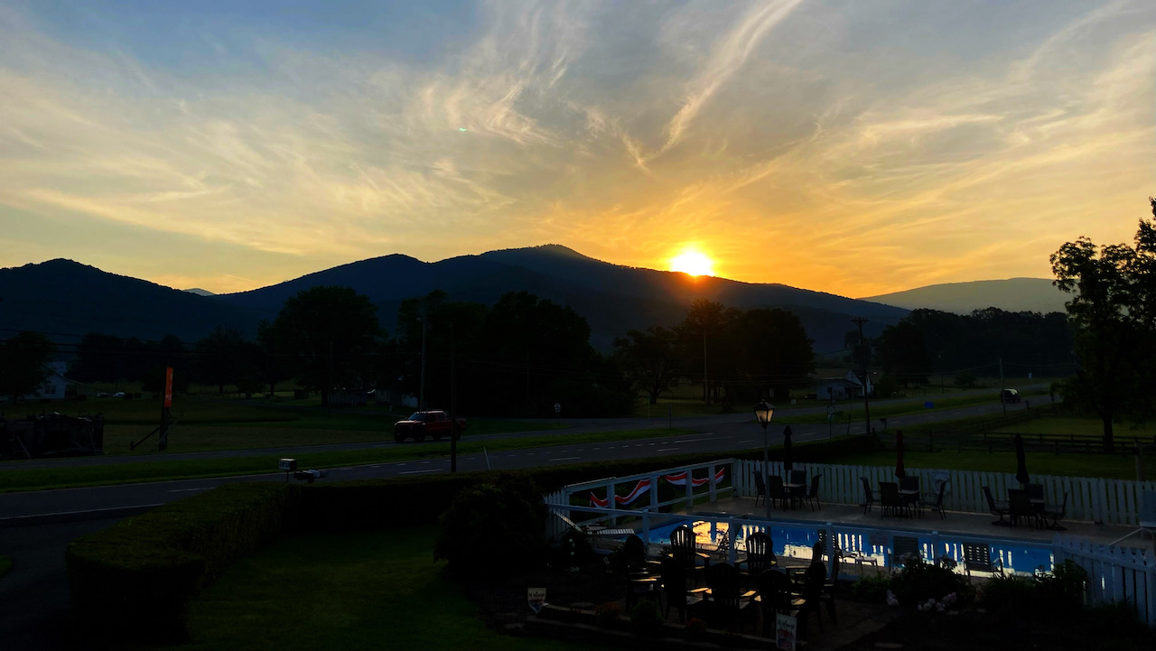 Sunrise over mountain, with swimming pool in foreground.