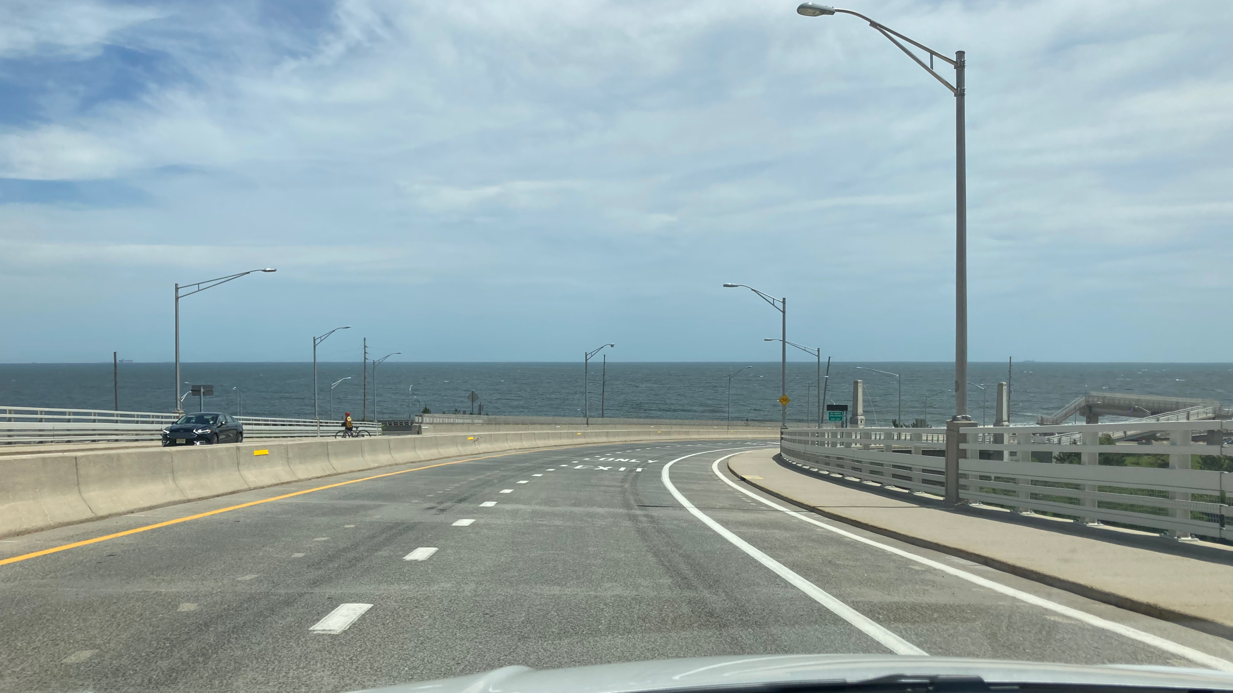 View of NJ Route 36 bridge toward Sandy Hook, with Atlantic Ocean in distance.