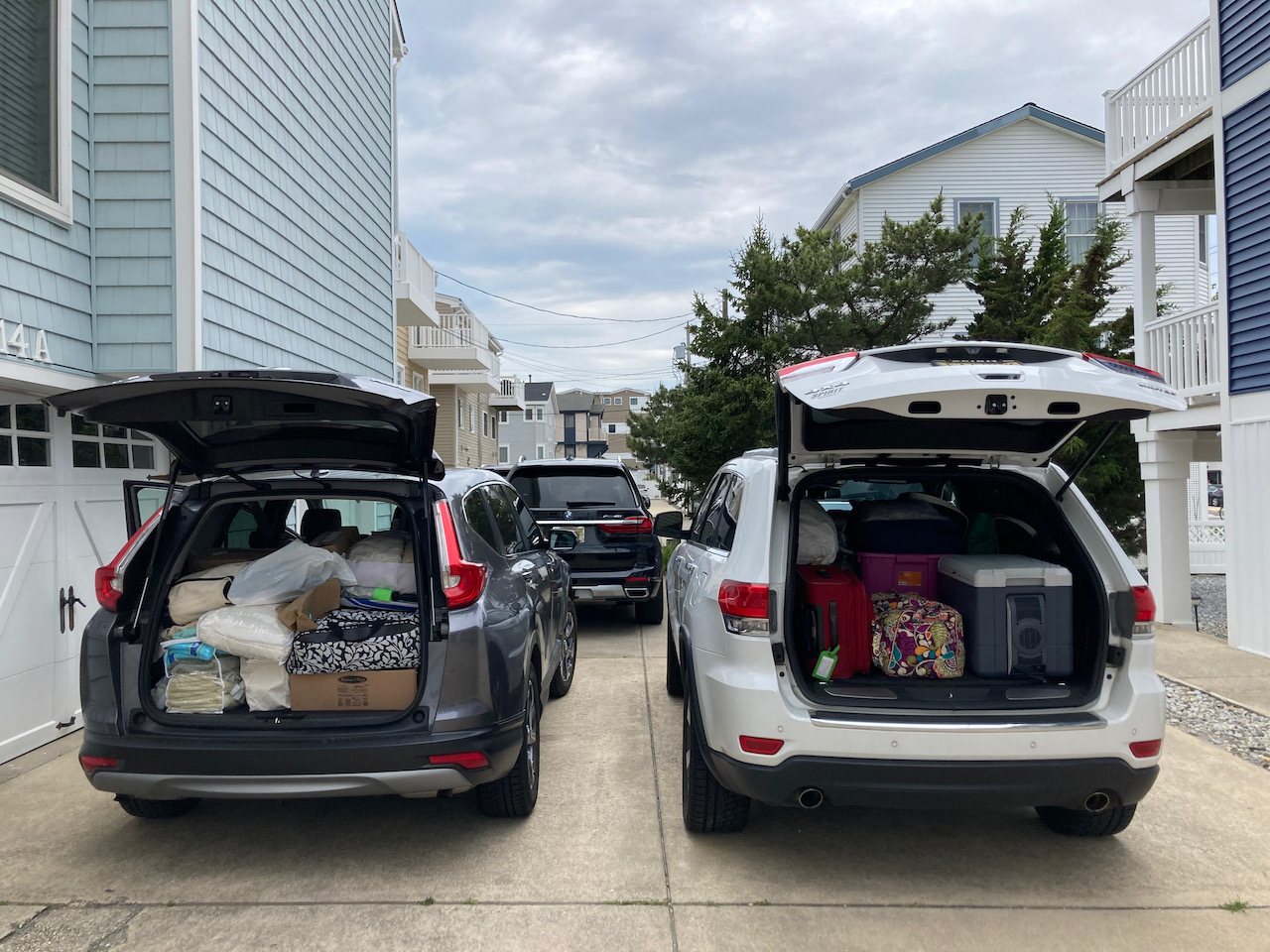 Honda CR-V and Jeep Grand Cherokee with trunks open, filled with items.