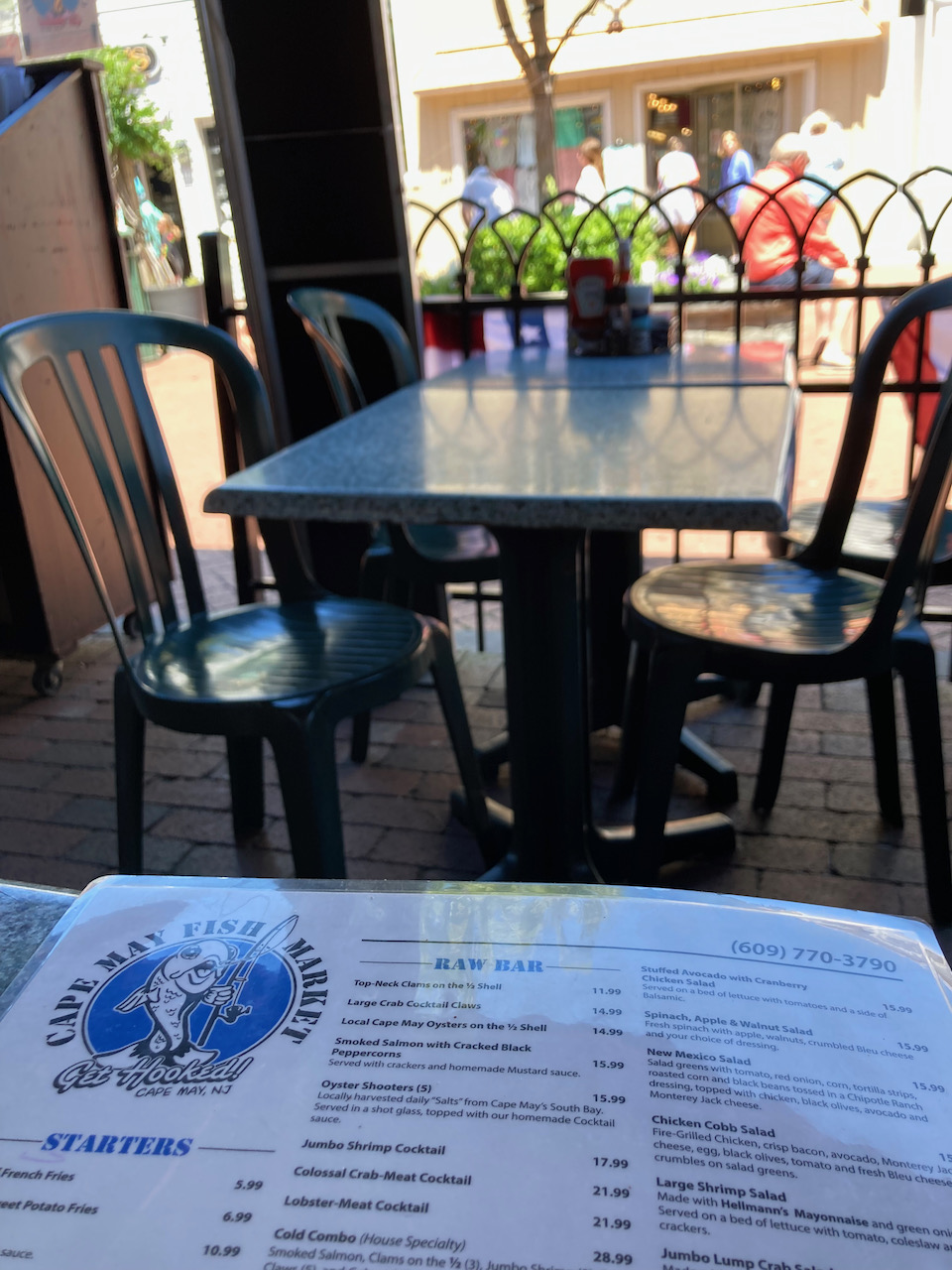 Menu of Cape May Fish Market in foreground, with empty table in background.