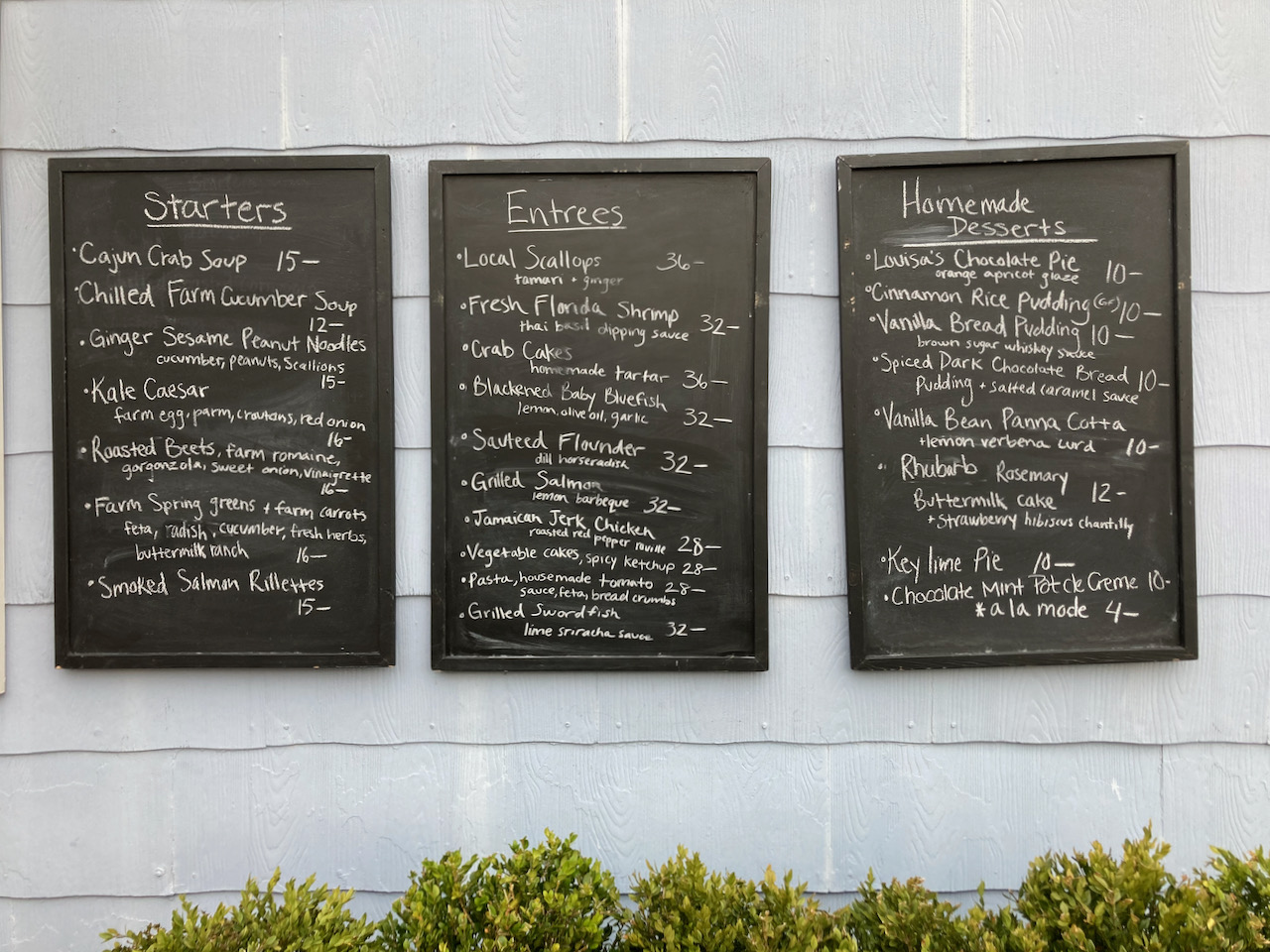 Three chalkboards on wall of building, with menu written on the boards.