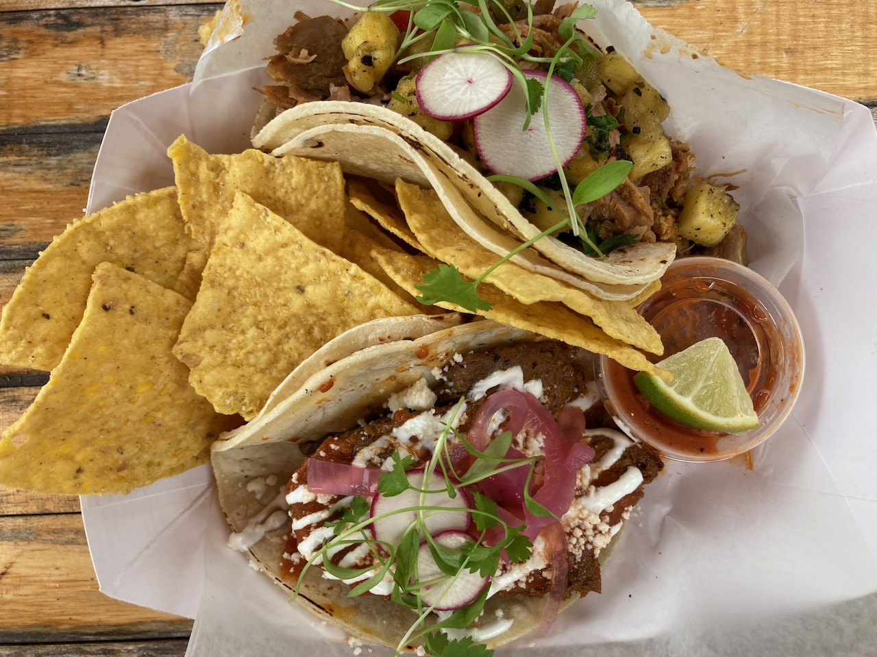Basket with two tacos, chips, and salsa.