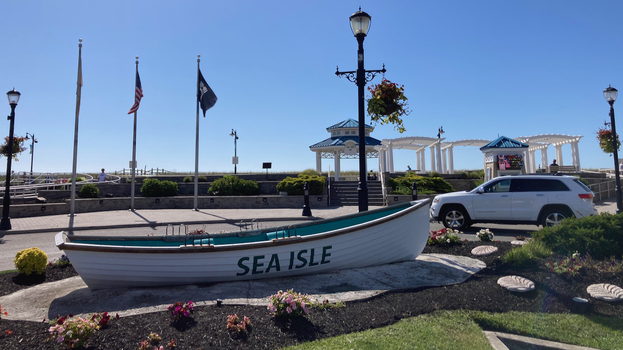 Rowboat with SEA ISLE painted on side, with Jeep Grand Cherokee in background.