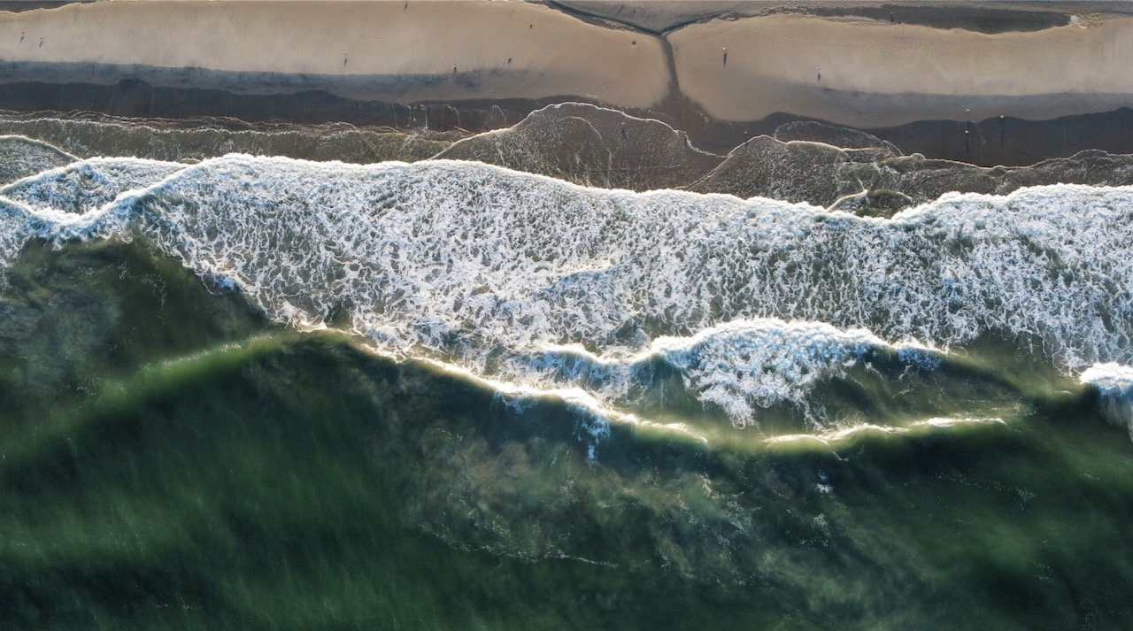 Aerial view of waves crashing against shore.