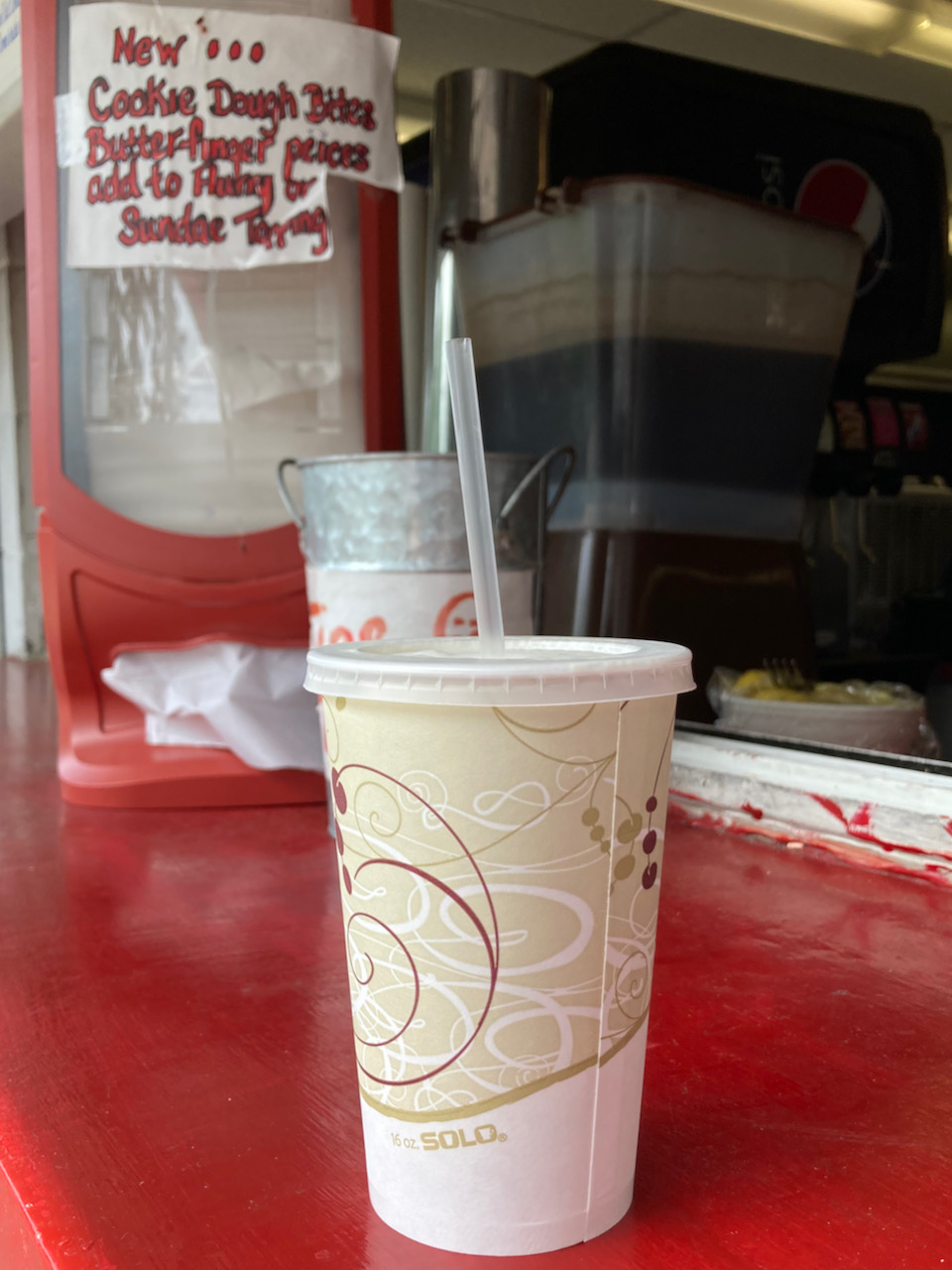 Paper cup with straw on red counter.