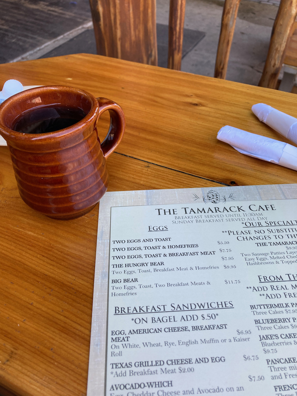 Menu for Tamarack Cafe and coffee cup on wooden table.