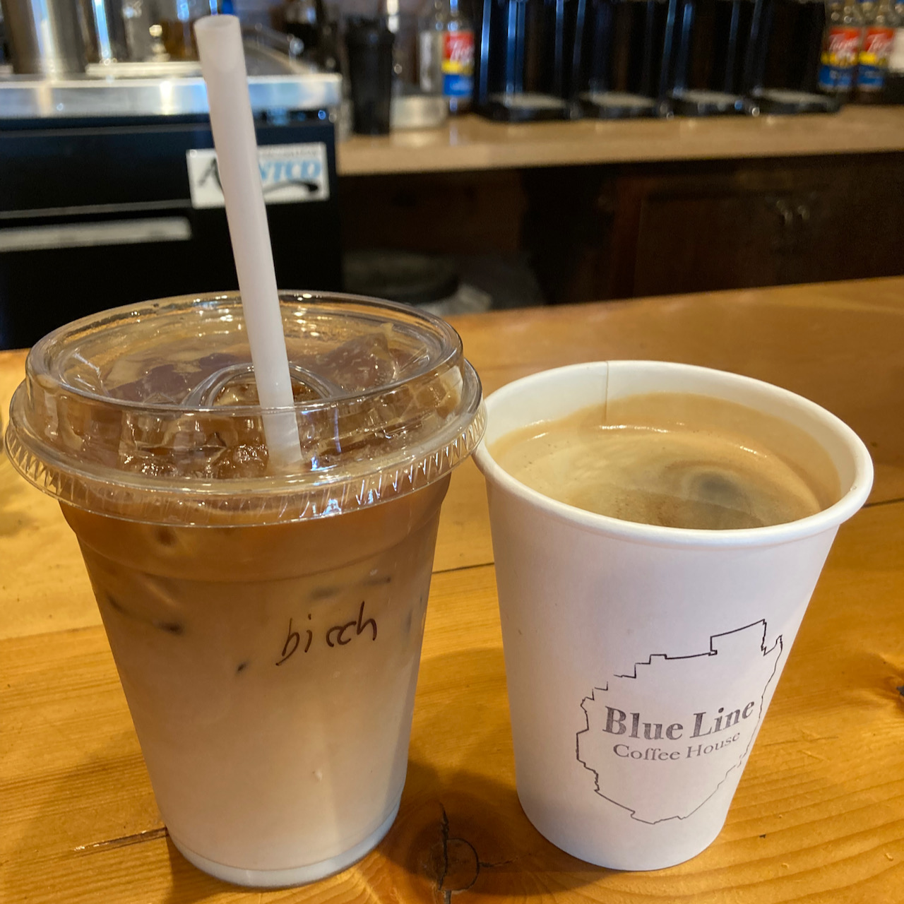 Iced coffee in plastic cup and hot coffee in paper cup.