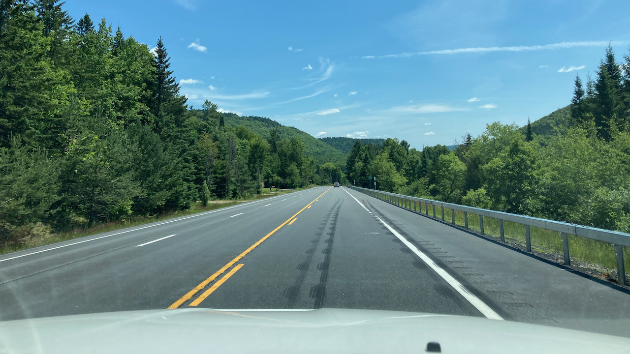 View of NY 28 on sunny day, with mountains in background.