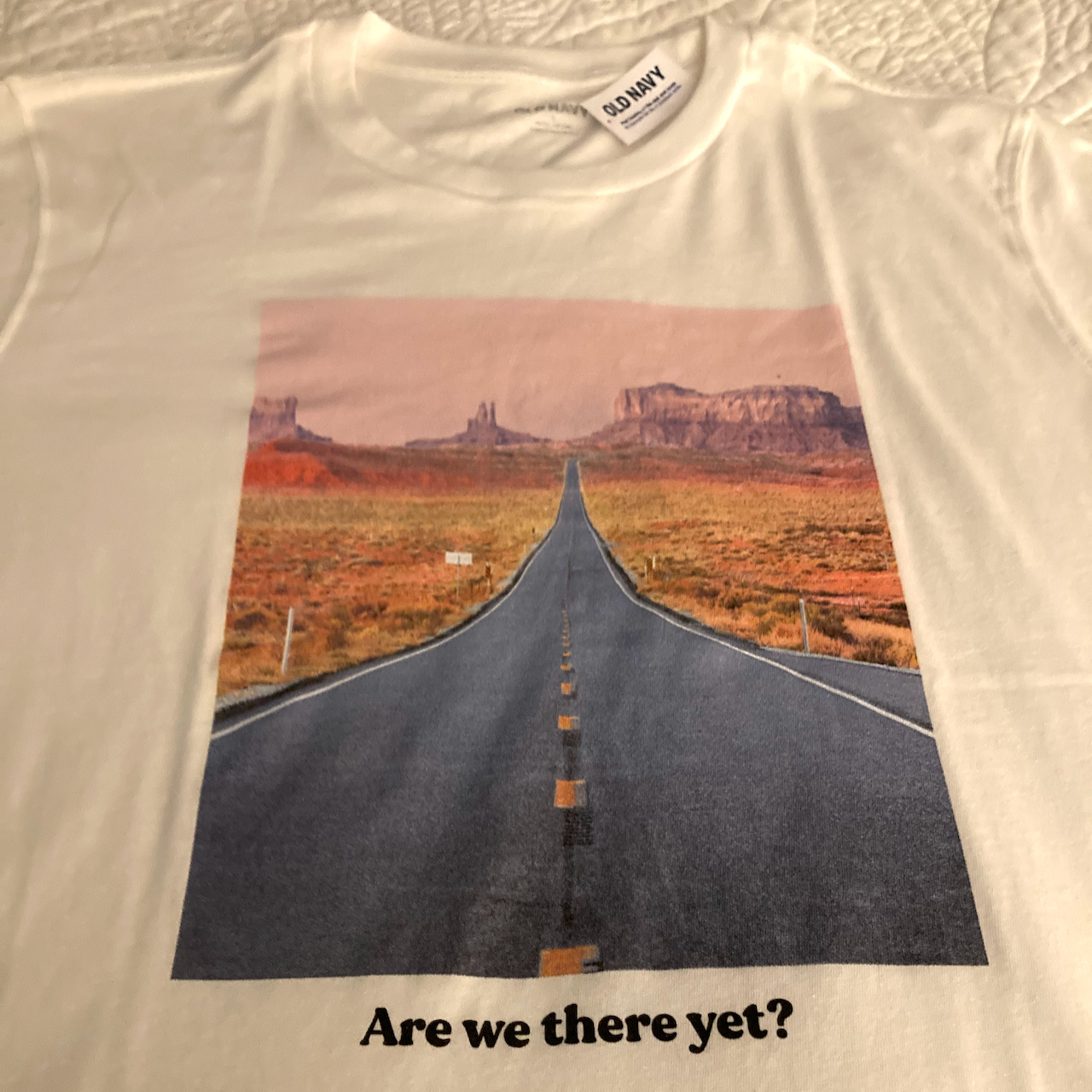 T-shirt with road leading to mountains and "Are we there yet" motto on bottom.