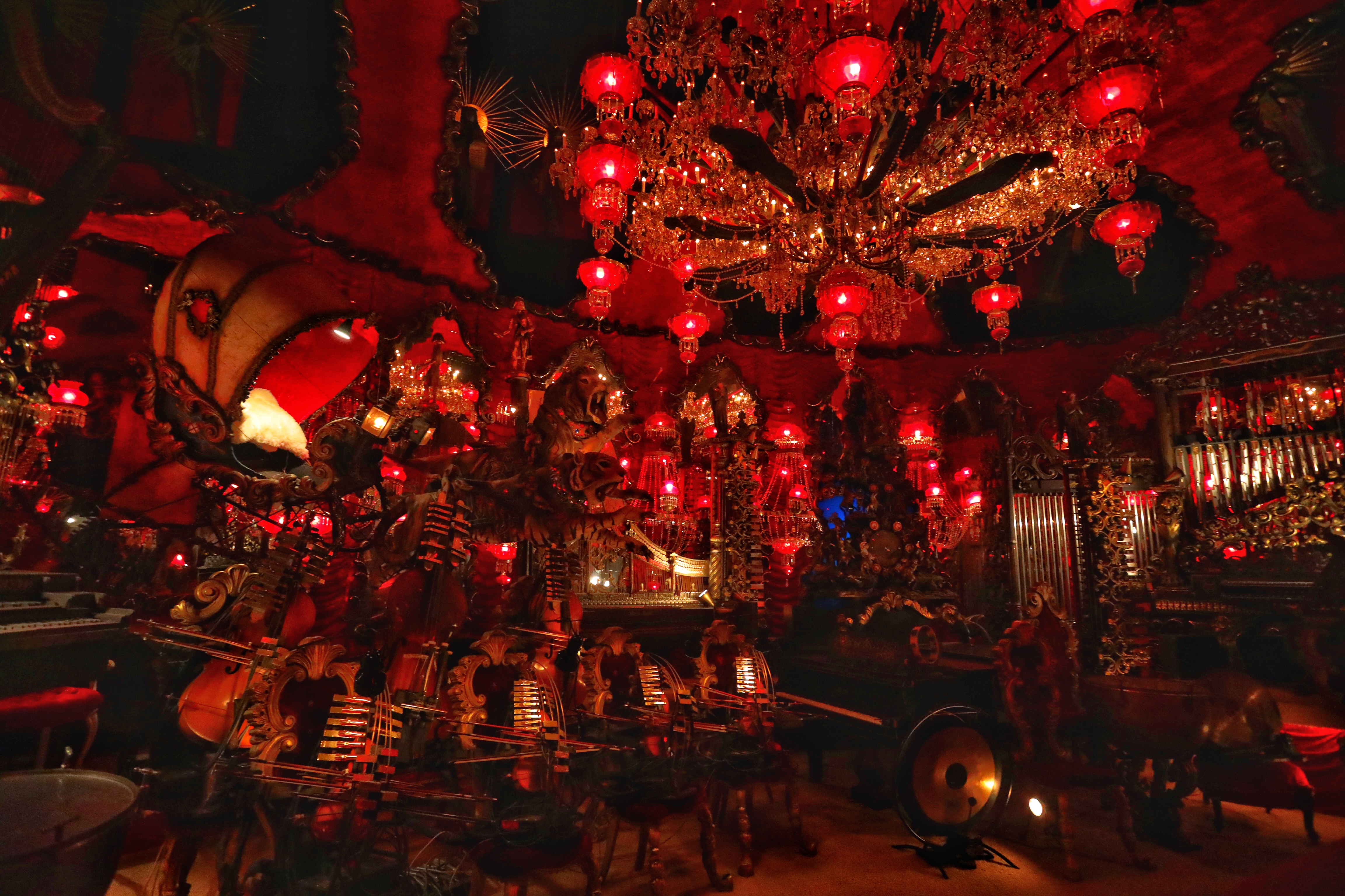 Red room with instruments and large chandelier.