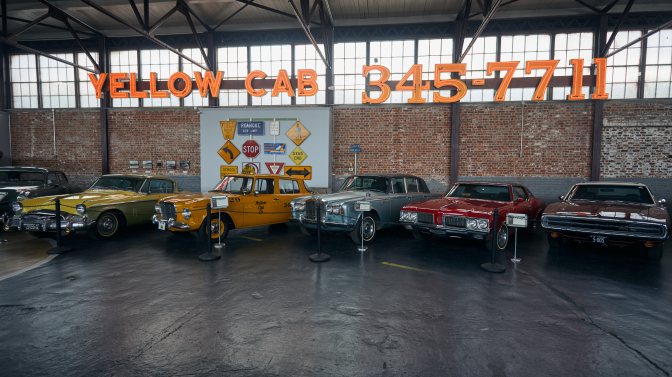 Series of classic cars beneath YELLOW CAB sign.