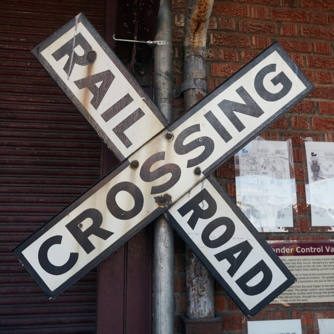 Railroad Crossing sign in front of brick wall.