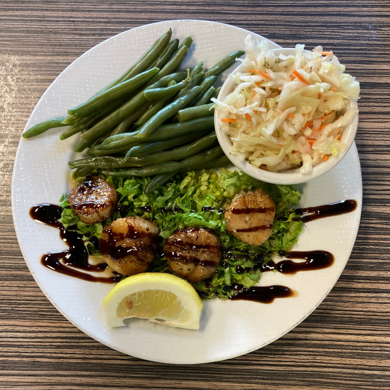Scallops, green beans, and slaw mix on plate.