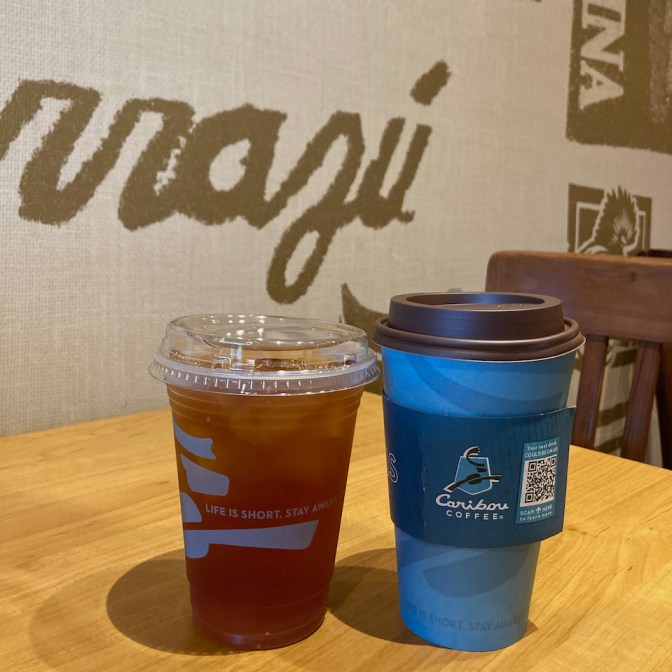 Iced tea and hot coffee on wooden table in coffee shop.