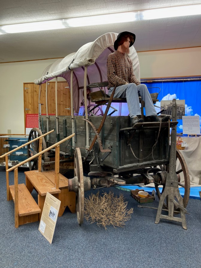 Prairie Schooner covered wagon, with mannequin in rider's seat.