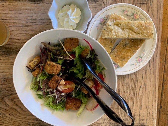 Salad, bread, and butter on table.