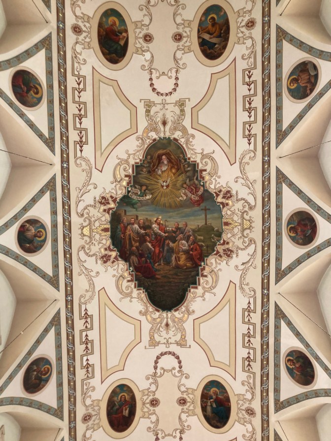 Ceiling of cathedral with saints and image of Christ heading to cross.