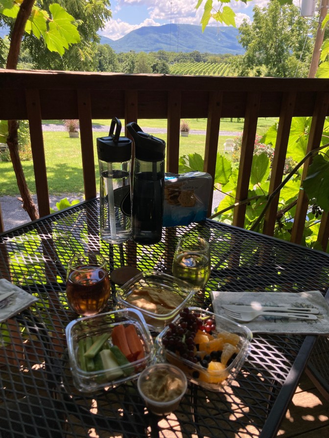 Two glasses of wine with picnic food on metal table.