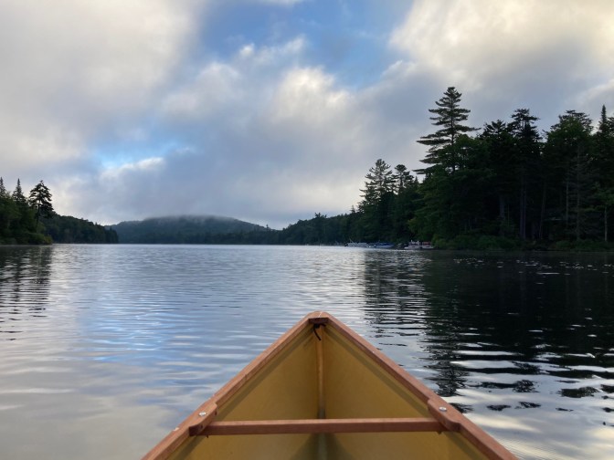 View of lake and mountains with canoe bow in foreground.