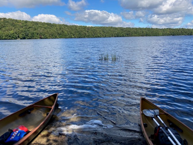 View of two canoes along lake bank.