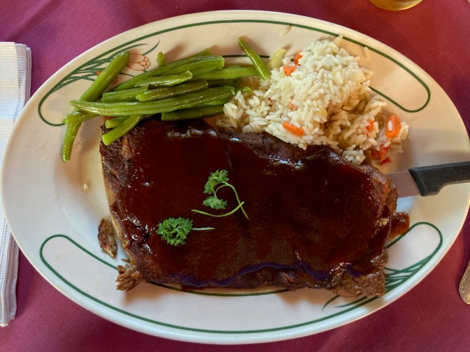 Ribs, rice, and green beans on plate.