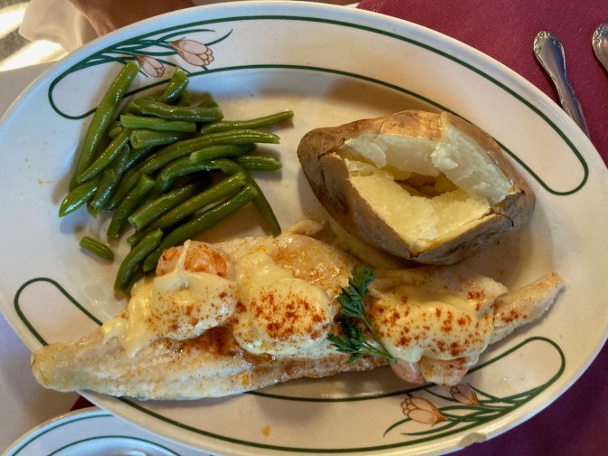 Haddock Mornay on plate with potato, green beans, and scallops.