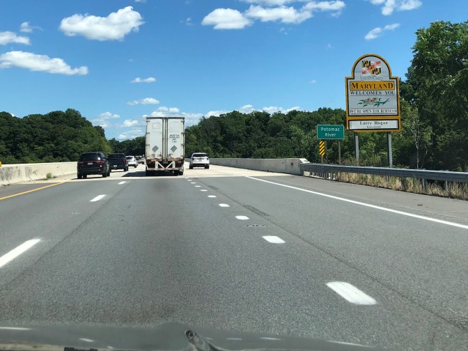 Interstate highway, with MARYLAND WELCOMES YOU sign beside road.