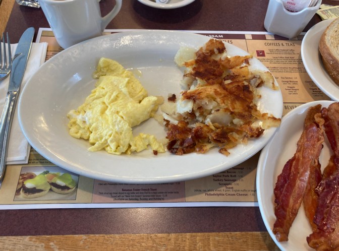 Scrambled eggs and home fries on white plate.