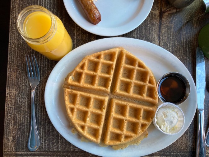 Waffle on plate with butter and syrup.