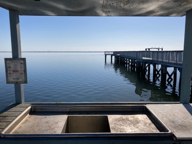 Sink and table for filleting fish, with pier in background extending out into water.