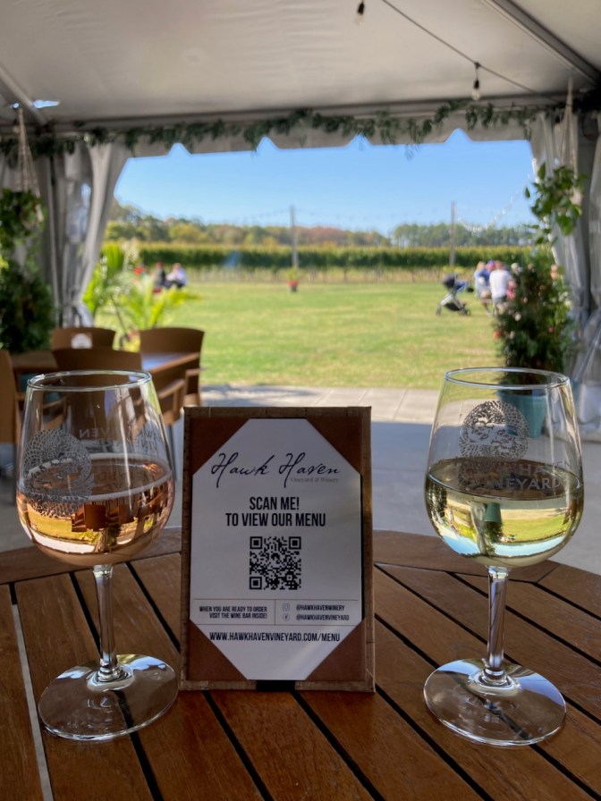 Two glasses of wine on table, with menu card for Hawk Haven Winery.