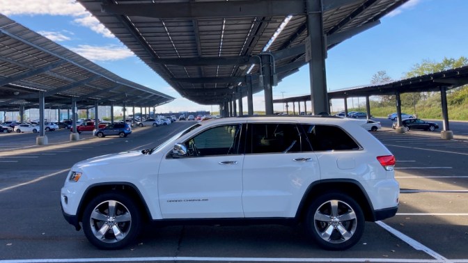 2014 Jeep Grand Cherokee parked in parking lot beneath solar panels.