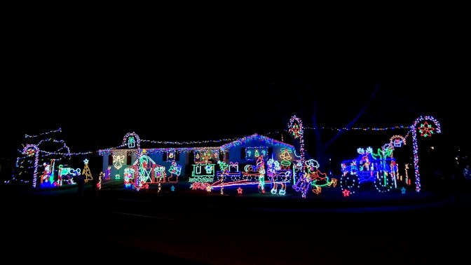 House decorated with Christmas lights and decorations on lawn.