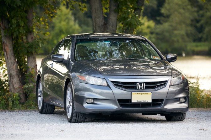 2012 Honda Accord coupe parked in gravel lot.