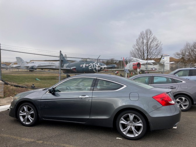 2012 Honda Accord, parked in front of fence, with military aircraft in background.