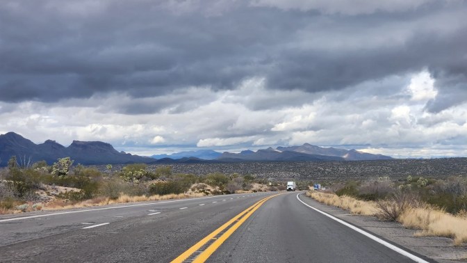US-93, under cloudy skies, with mountains in the distance.