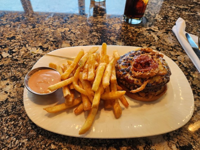 Bison burger on plate, with fries and mustard.