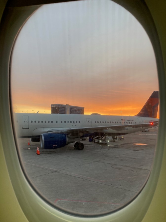 View of airplane and airport through window of airplane.