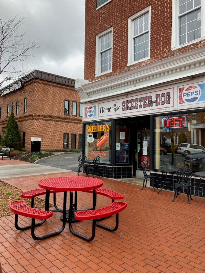 Exterior of Skeeter's restaurant, with a red metal picnic table on sidewalk in foreground.