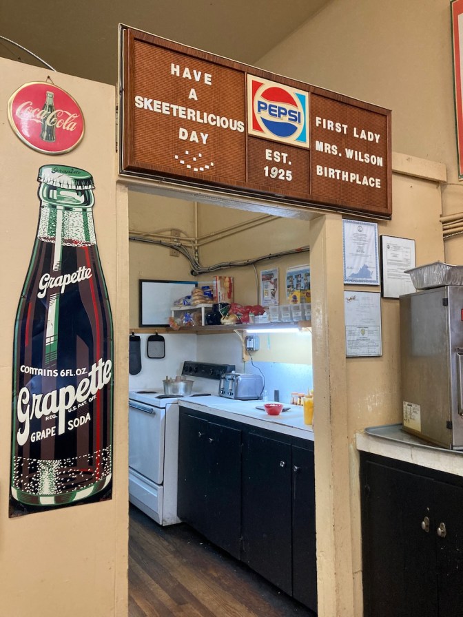 Kitchen of Skeeter's. Sign above doorway says PEPSI EST 1925 HAVE A SKEETERLICIOUS DAY FIRST LADY MRS WILSON BIRTHPLACE.