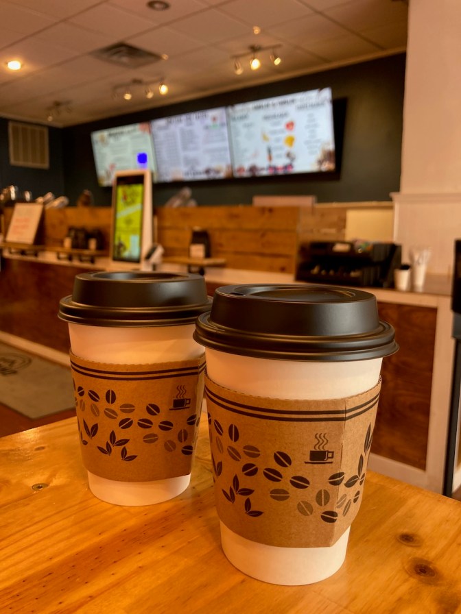 Two cups of coffee on counter in coffee shop.