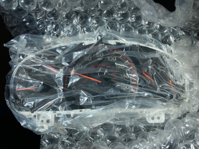 Gauge cluster, wrapped in plastic wrap.