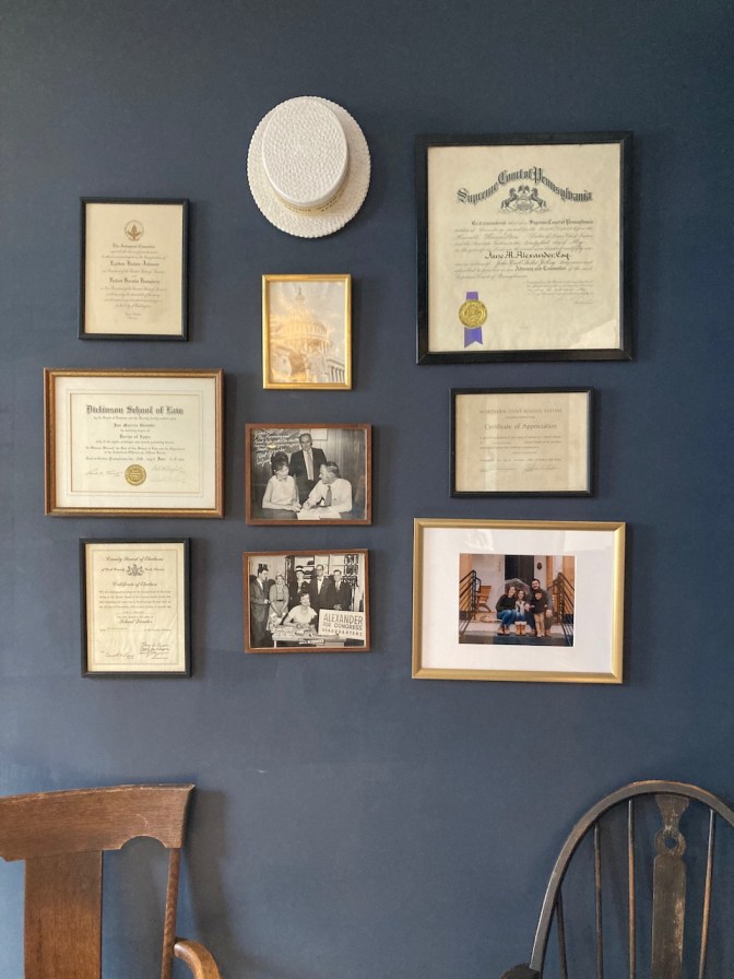 Wall with photos, plaques, and a hat.